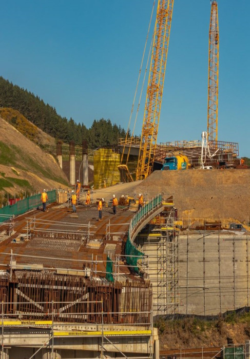 Building construction site with construction workers, two cranes steel fixtures