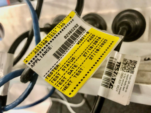 A test and tag label on the cord of a PC showing dates, status and tester information.