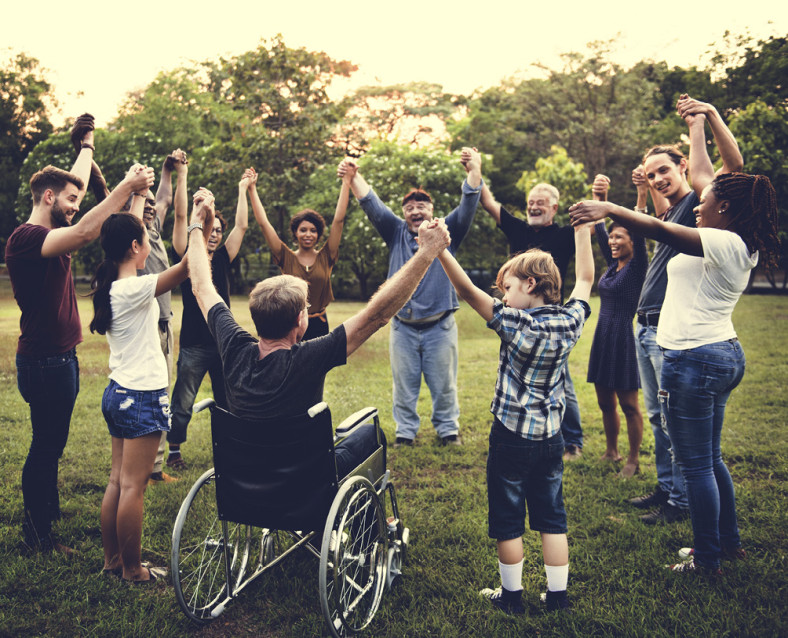 A group of people in a circle, holding hands up high 